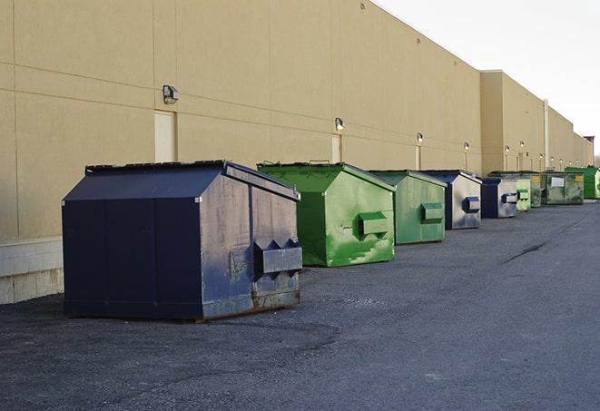 construction workers loading debris into dumpsters on a worksite in Carlyss